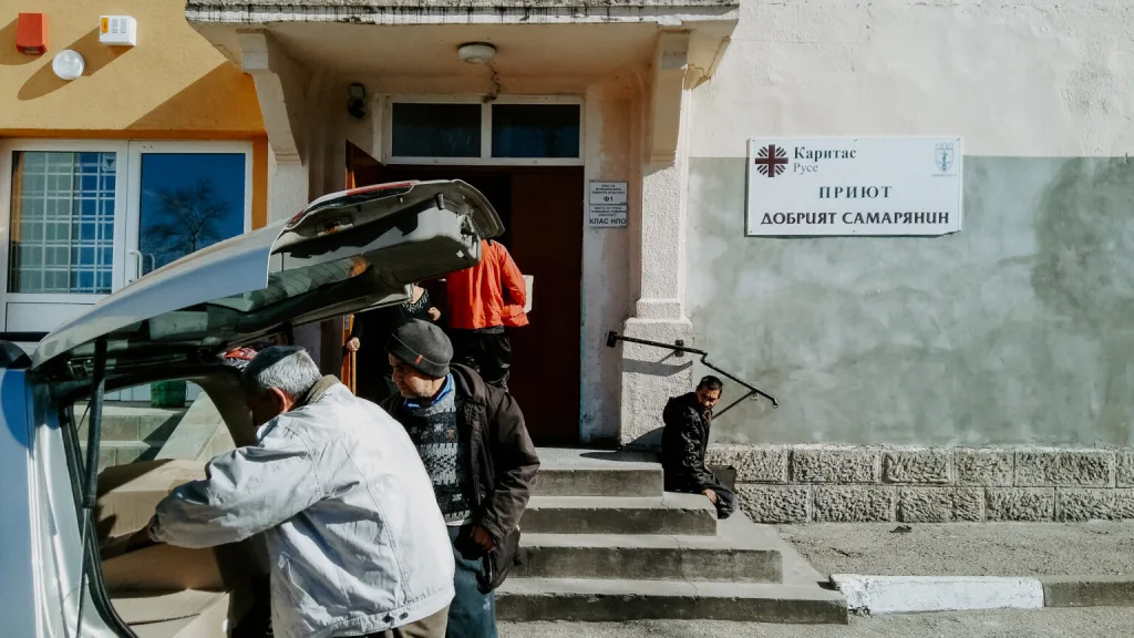Two men look into the back of a car outside a homeless shelter